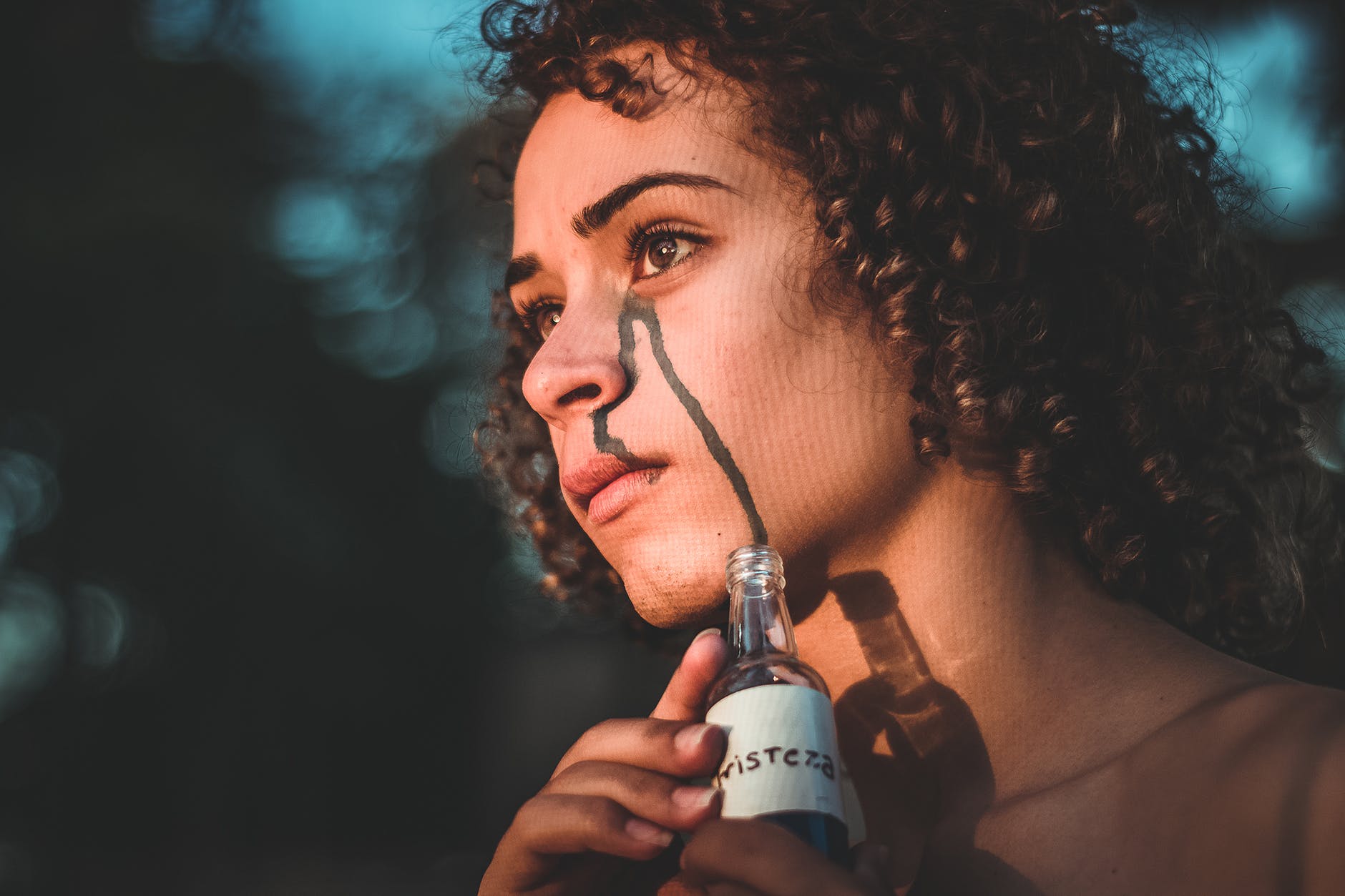 selective focus photography of woman holding clear glass bottle