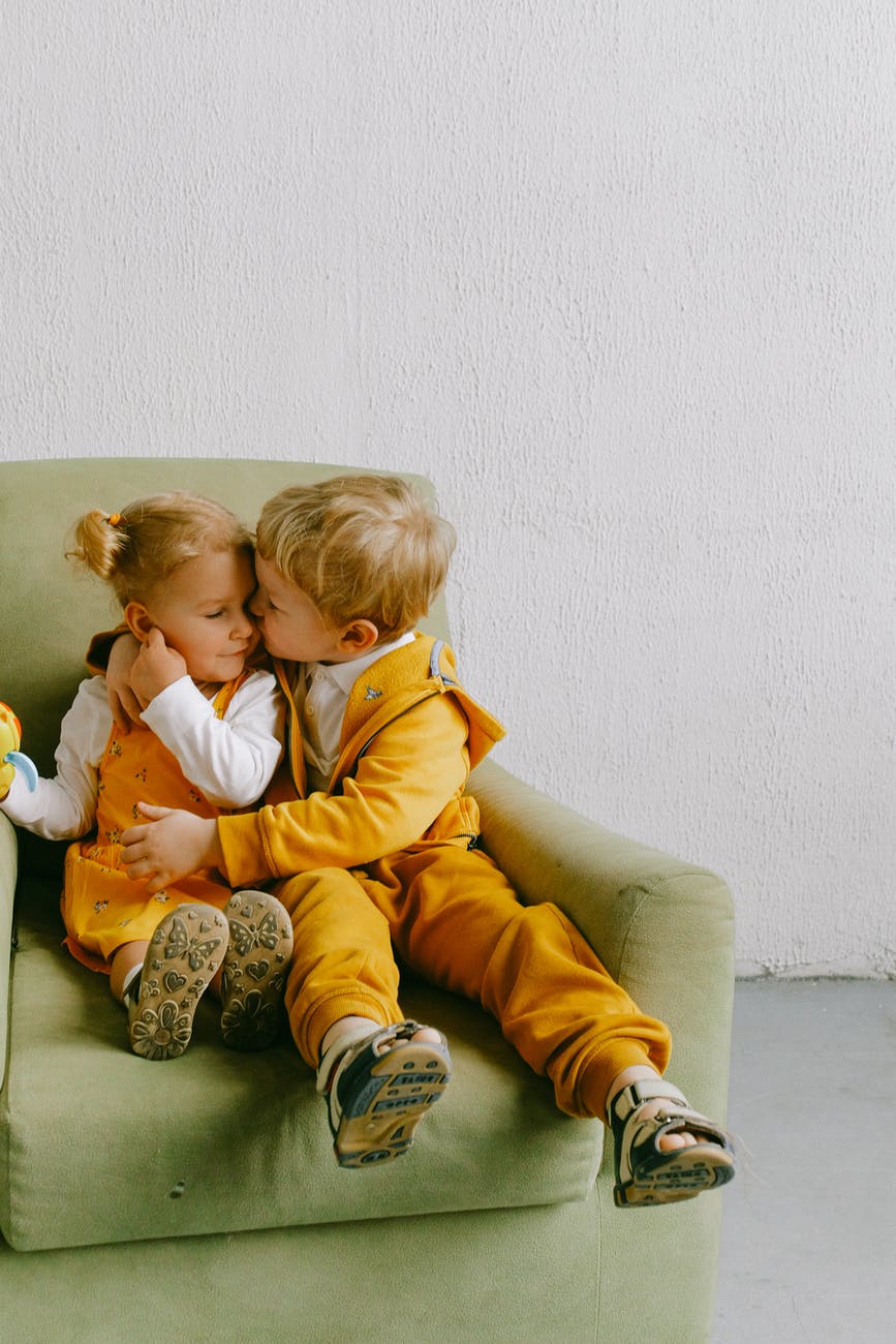 cute children cuddling in armchair at home