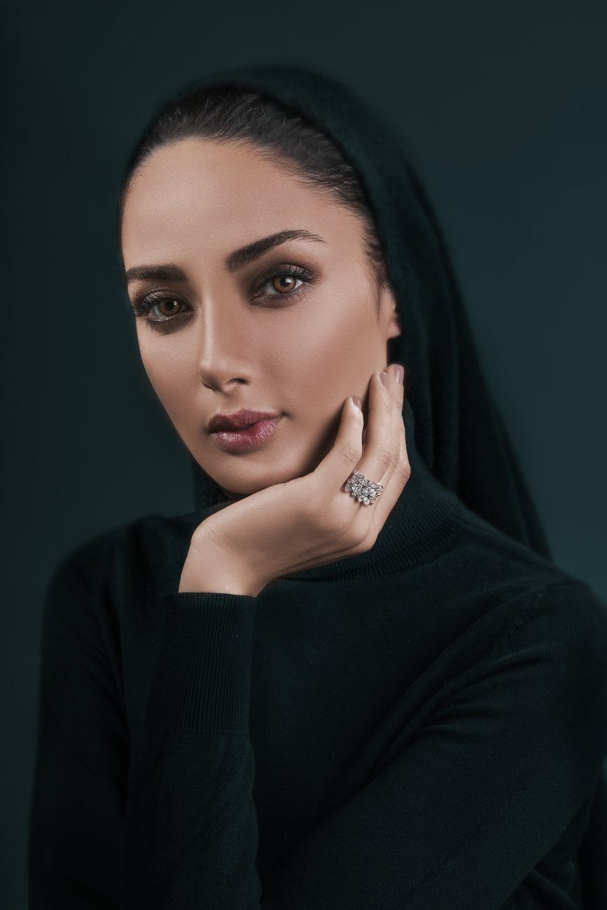 serene attractive woman covering head with black scarf in studio