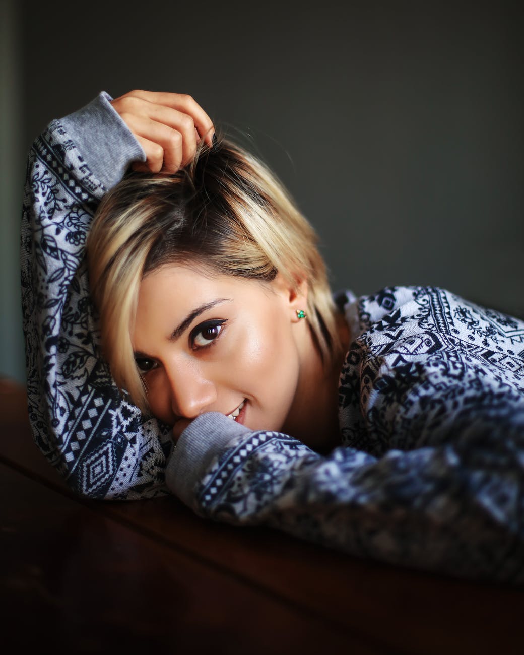 cheerful woman resting head on arm in dark room