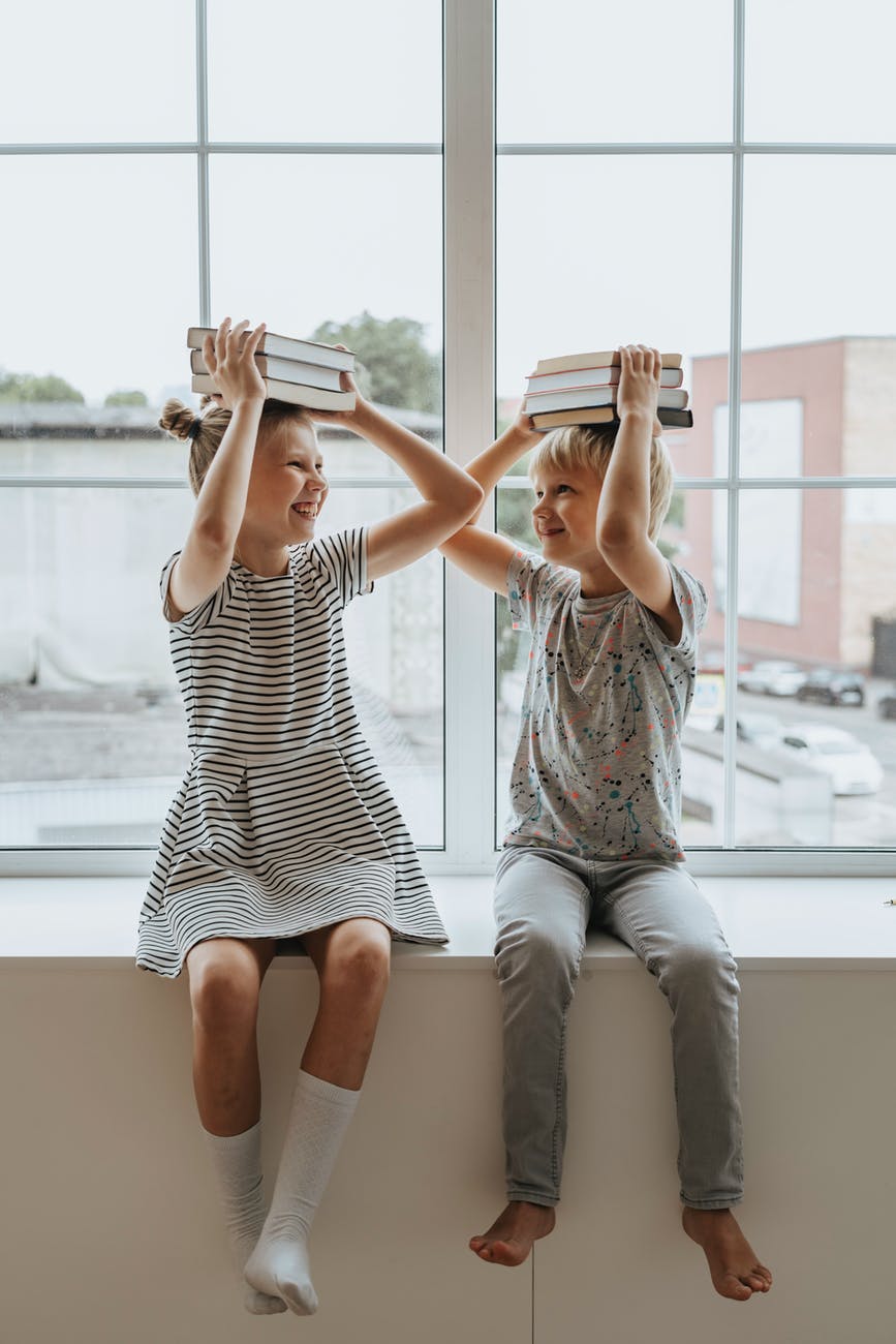 brother and sister with books on their heads