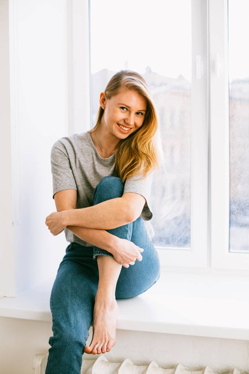 smiling female in casual clothes on windowsill